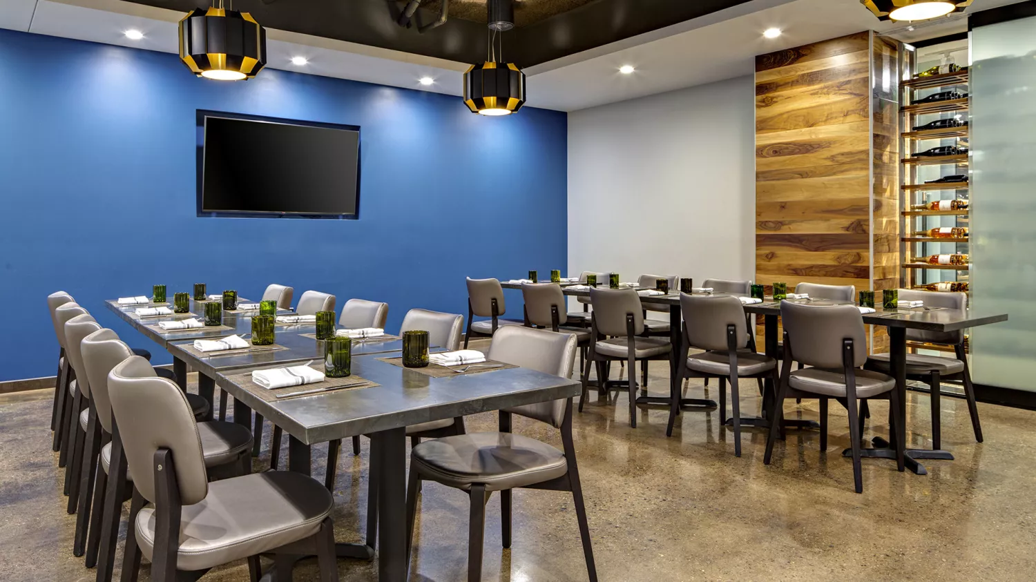 Amway Grand_The Kitchen by Wolfgang Puck_Private Dining Room_Two Long Tables_Chairs_TV_Wine Rack_Candles_Napkins_Hanging Lights