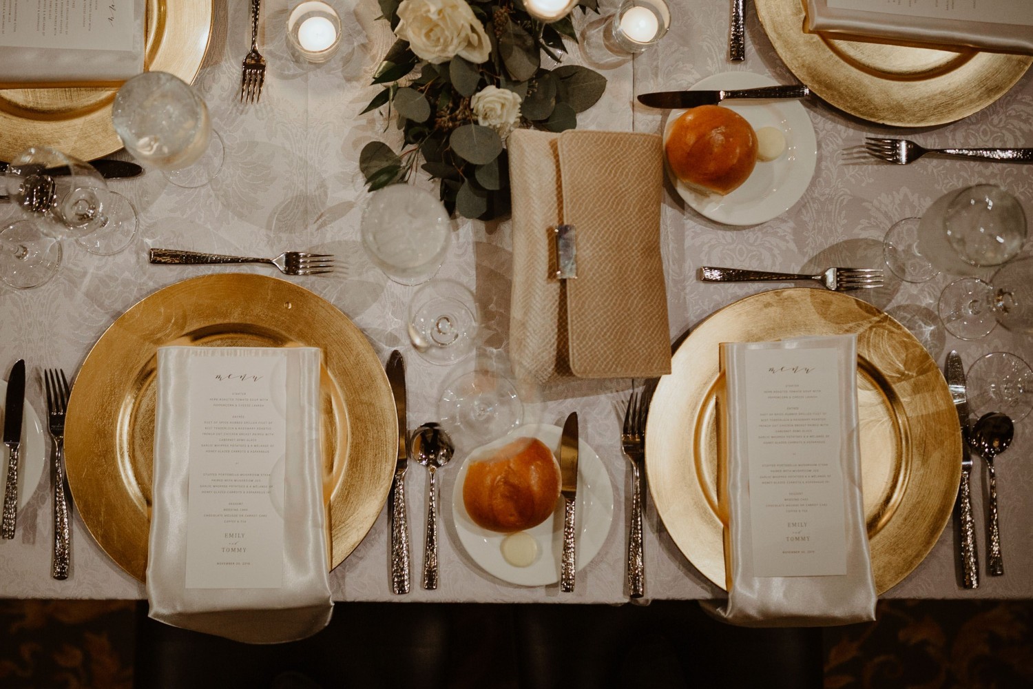 Amway Grand_Wedding_Set Up_Plates_Silverware_Glasses_Rolls_menu_Flowers_Greenery_Candles_Linen